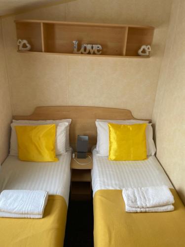 塔特舍尔Calypso Hot Tub Breaks Tattershall Lakes Pet Friendly的小房间设有两张带黄色枕头的床