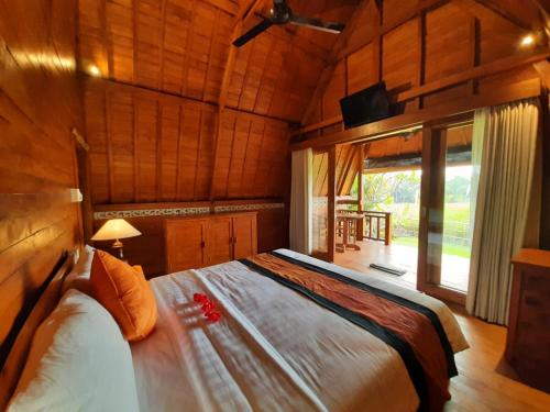 乌布Pondok Gandalangu Ubud-Dikelilingi Hamparan Sawah的木制客房内的一间卧室配有一张大床