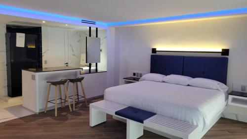 墨西哥城WeEnjoy Hotels Grand Prix Aeropuerto CDMX的一间带白色床的卧室和一间厨房