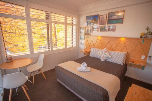 皇后镇Absoloot Hostel Queenstown的卧室配有一张床和一张桌子及椅子