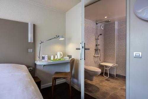 马孔The Originals City, Hôtel Mâcon Nord的酒店客房设有一张床和一间带淋浴的浴室。