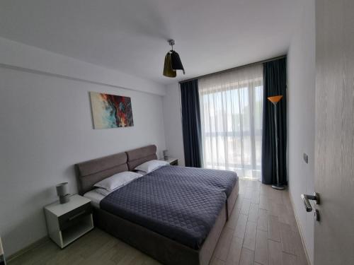 马马亚RoApart Mamaia - Riva Lake Apartments的一间卧室设有一张床和一个大窗户