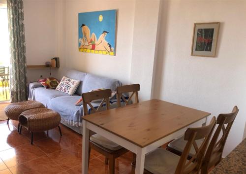 帕洛斯角Cala Reona Holiday Apartment的客厅配有桌子和沙发