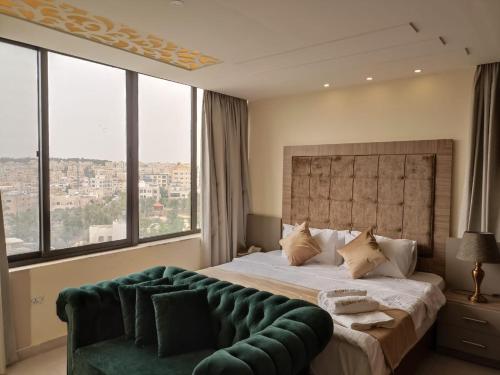 安曼AlQimah Hotel Apartments的一间卧室配有一张大床和绿色沙发