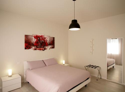 BroglianoMelograno Rooms B&B的白色卧室配有一张床,墙上挂着一幅画