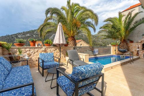 赫瓦尔Villa Capitis in the center的一个带椅子和遮阳伞的庭院和一个游泳池