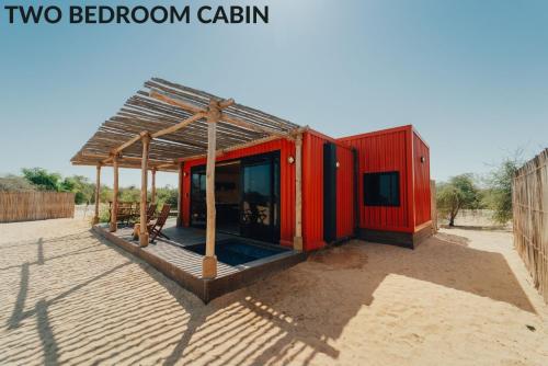米尔费Bab Al Nojoum Al Mugheirah的沙漠中一座有屋顶的红色小建筑