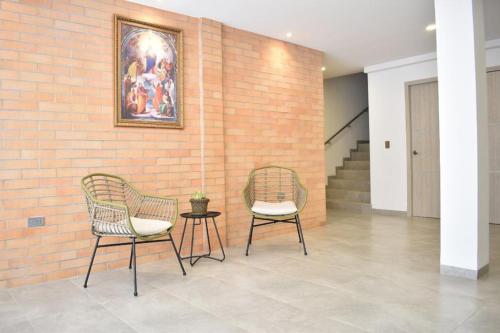 库库塔Hotel Blu Cúcuta的砖墙旁的两把椅子和一张桌子
