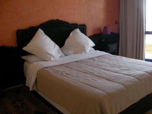 西迪伊夫尼萨法酒店的一间卧室配有带白色床单和枕头的床。