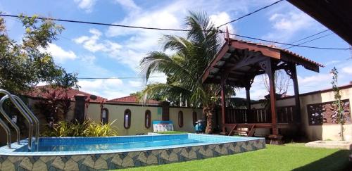 马六甲Achutra Muslim Guesthouse (pool)的一座带游泳池和凉亭的房子