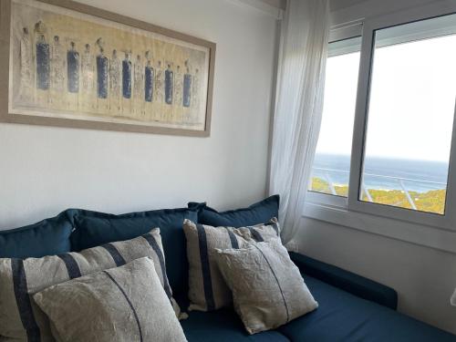 帕尔斯Apartamento en Playa de Pals con encanto y vistas的窗户客房内的蓝色沙发及枕头