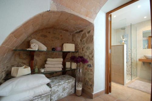 滨海托萨Lets Holidays Tossa de Mar Romantic Apartment的浴室设有石墙、一张床和淋浴