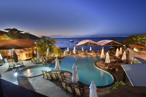 布希奥斯Hotel La Forêt & Beach Club的享有带遮阳伞和椅子的游泳池的景色