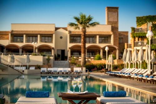 赫索尼索斯贝拉海滩酒店的一个带躺椅的游泳池和一间酒店