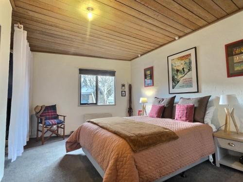 丁诺高原Snow Gums Apartment 4, alpine-getaways的一间卧室设有一张带木制天花板的大床