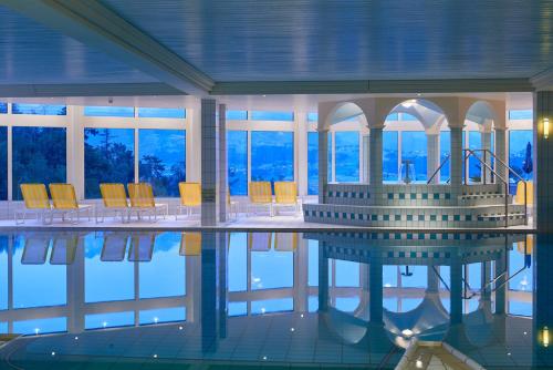 锡格里斯维尔Panorama Boutique Apartment with complimentary Spa access at Solbad Hotel的大楼内一个带椅子和桌子的游泳池