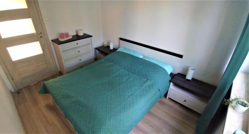 苏瓦乌基M&M Suwałki Centrum的一间卧室配有一张带绿色棉被的床