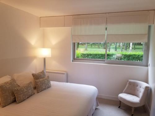 图尔热维尔Deauville vue mer的一间卧室设有一张床、一个窗口和一把椅子