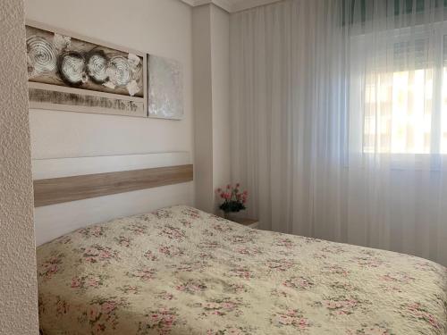 博尔瑟拉尔Apartment in Oropesa Del Mar Marina Dor的一间卧室配有一张带花卉床罩的床和窗户。