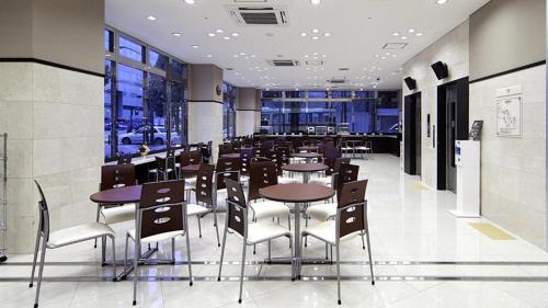 平冢市Toyoko Inn Shonan Hiratsuka eki Kita guchi No 1的餐厅设有桌椅和窗户。