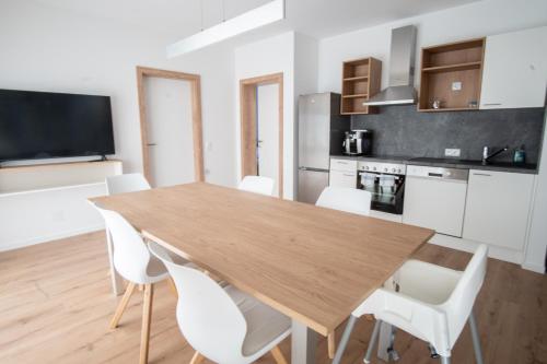 路茨曼贝格Family XL - Bungalows的厨房以及带木桌和白色椅子的用餐室。