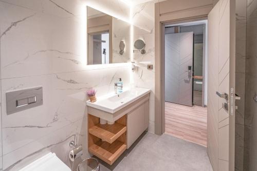 拉瑞New Safir Apart Hotel的白色的浴室设有水槽和淋浴。
