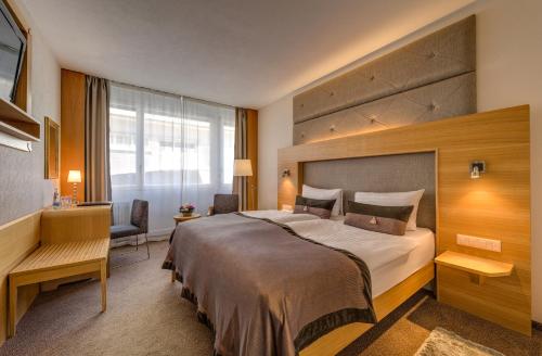 洛桑洛桑市大陆酒店的酒店客房设有一张大床和一张书桌。