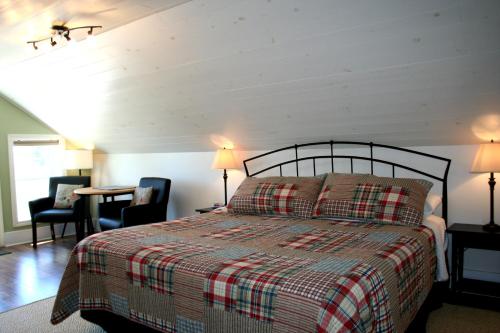 惠灵顿Hadovka Lakeside Inn的一间卧室配有一张床、两把椅子和一张桌子