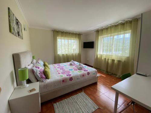 吉尔斯Cantinho Verde T2的卧室配有床、桌子和窗户。
