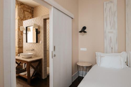 科维良Casa das Muralhas的卧室配有白色的床和水槽
