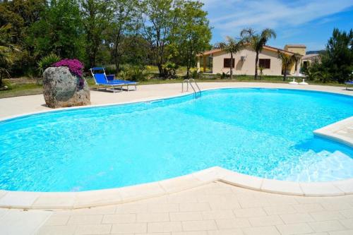 阿尔布斯Agriturismo Rocce Bianche - Porticato的一个带椅子和房子的大型蓝色游泳池