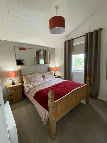 达农Cherry tree Lodge的一间卧室配有一张带红色毯子的木床