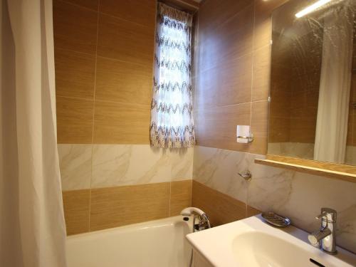 尚鲁斯Appartement Chamrousse, 2 pièces, 6 personnes - FR-1-549-53的带浴缸、水槽和镜子的浴室