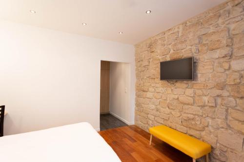 巴黎Hotel Mimosa Paris的一间卧室设有石墙、一张床和一张黄色长凳