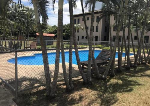利比里亚Apartamento The Garden的棕榈树泳池旁的围栏,带长凳