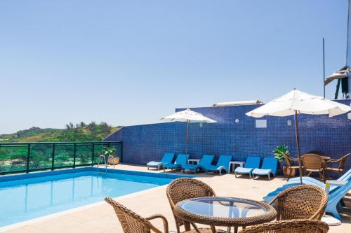 阿拉亚尔-杜卡布Mediterrane Hotel by Castelo Itaipava的游泳池配有椅子、桌子和遮阳伞