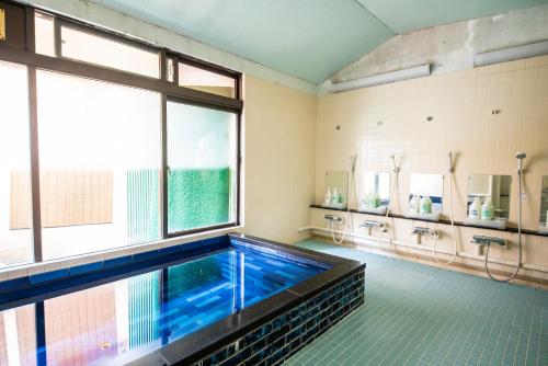 京都京都駅前ひふみ旅館（HifumiRyokan Kyoto station)的一个带游泳池和两个水槽的大浴室