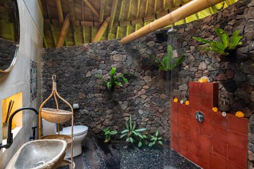 乌布Bamboo Turtles Ecolodge的一间带卫生间和石墙的浴室