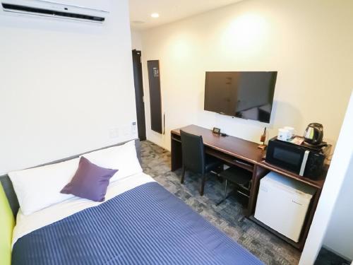 新泻HOTEL LiVEMAX Niigata Ekimae的酒店客房配有一张床和一张书桌及一台电视