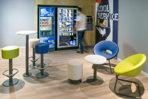 沙西约宜必思里昂国际展会经济酒店的冷藏箱前的一组椅子和凳子