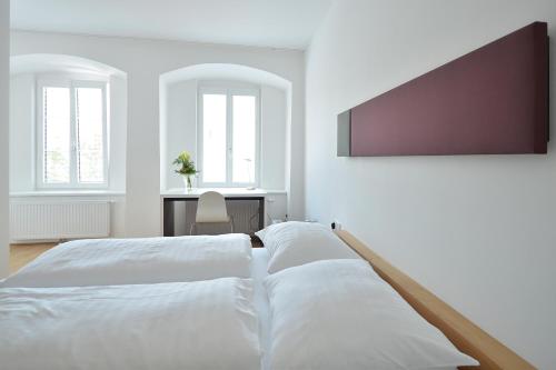 恩斯佐姆戈登施尼弗酒店的一间白色卧室,配有两张床和一张书桌