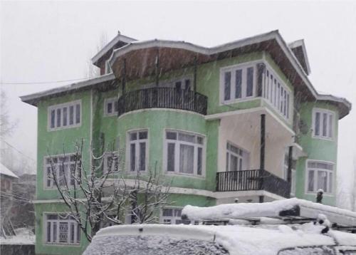 斯利那加Calm Holiday Inn的一座绿色的白色房子,里面积雪