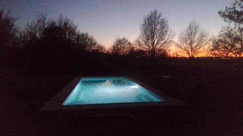 ChaumontLe Petit Chaumont Ecolodge的日落时在田野中间的游泳池