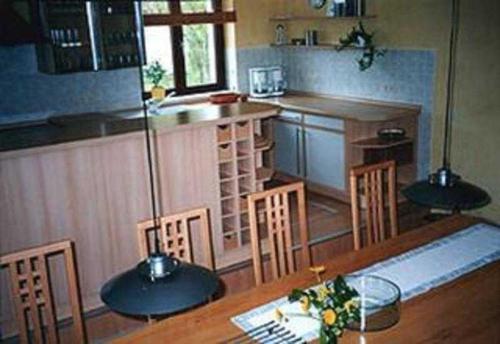 KampFerienhaus Kamp Familie Diebenow的厨房配有木桌、椅子和柜台
