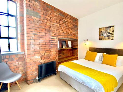 布里斯托Victorian Factory Apartment with 2 Bedrooms的一间卧室设有砖墙和一张黄色枕头的床