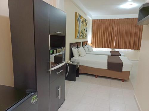 比亚埃尔莫萨HOTEL VILLA MARGARITAS的配有床和冰箱的酒店客房
