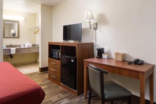 鸽子谷Americana Inn a Travelodge by Wyndham的酒店客房配有一张书桌、一台电视和一张床