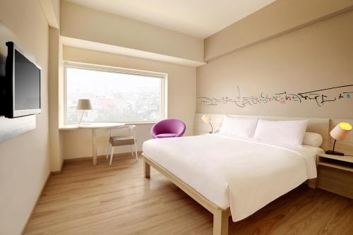 雅加达雅加达卡查玛达宜必思尚品酒店的一间卧室配有一张床、一张书桌和一个窗户。