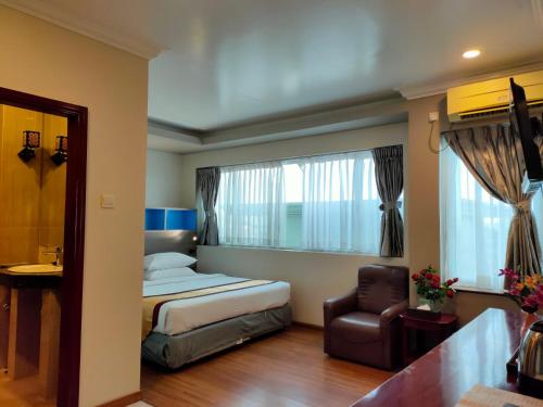 仰光联合大酒店（阿弄店）的卧室配有床、椅子和窗户。