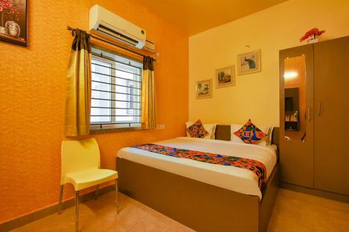 钦奈FabHotel Vijaylakshmi Stay Inn的一间卧室设有一张床、一个窗口和一把椅子